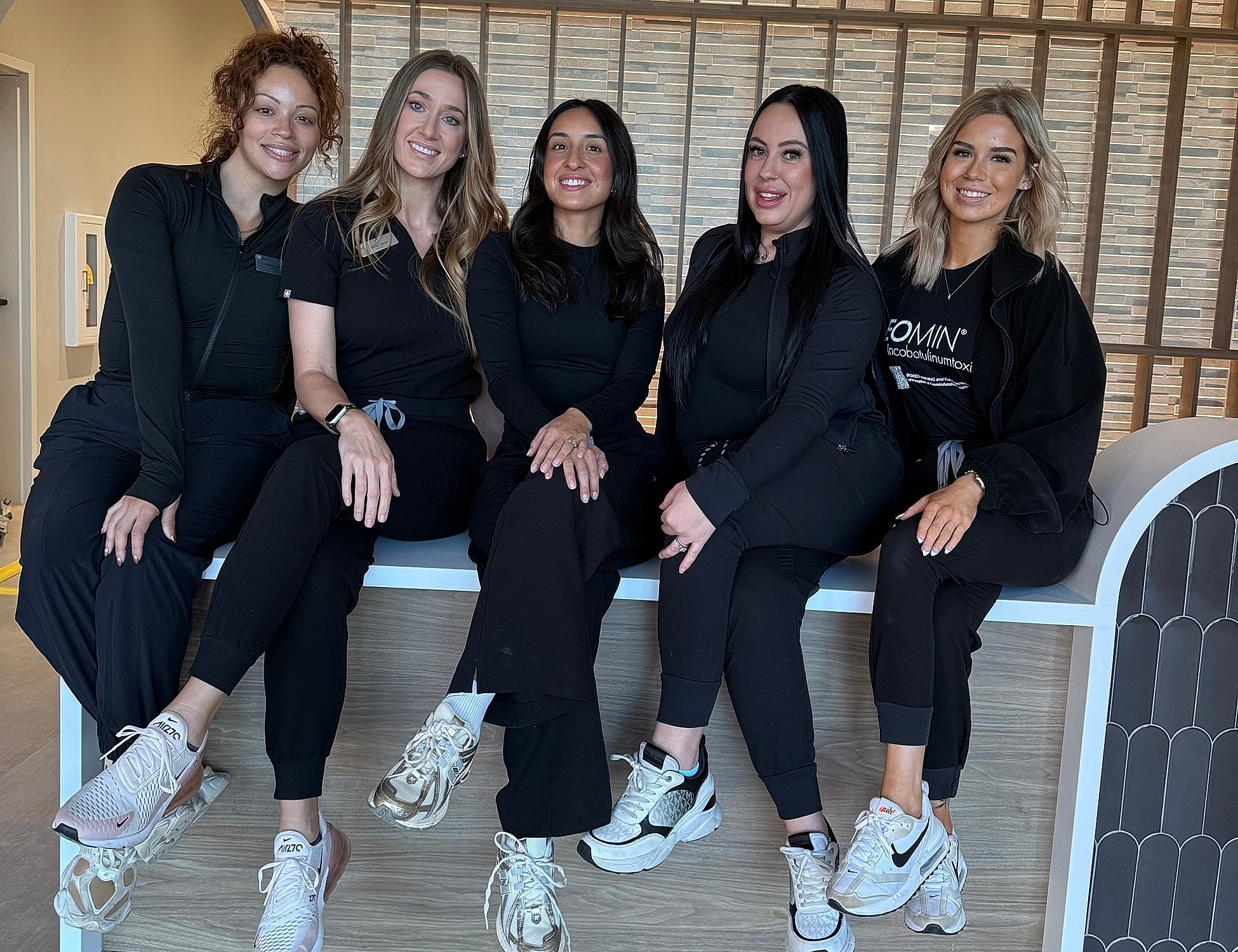 Group of five women posing together indoors.