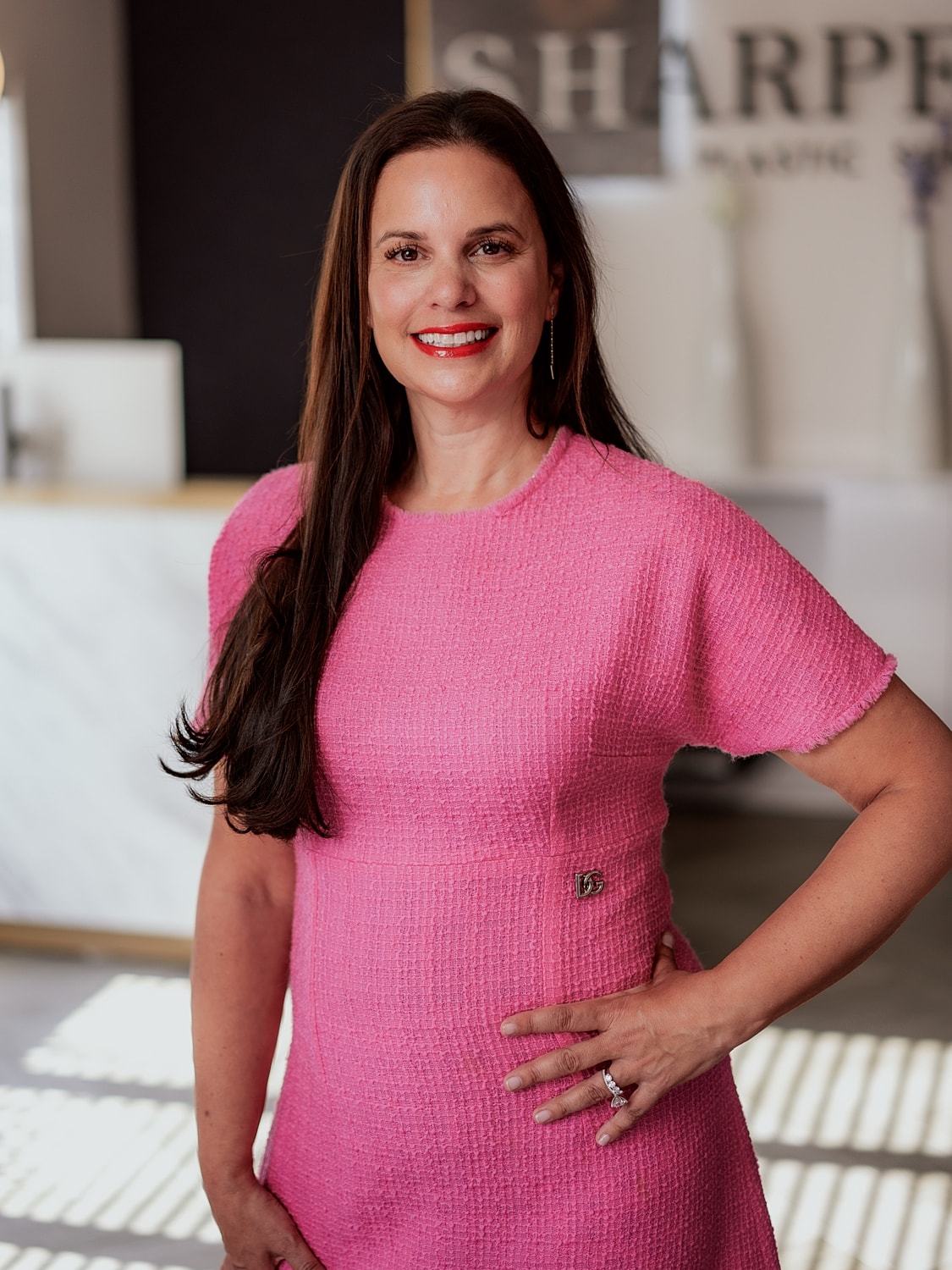Woman in pink dress smiling confidently indoors.