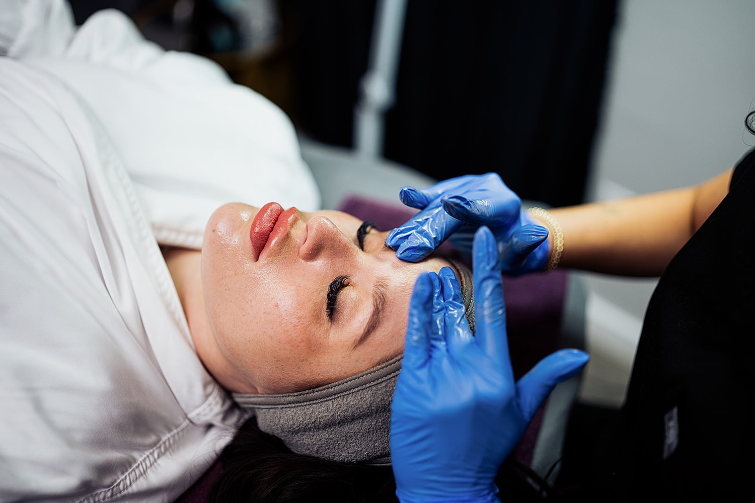 Facial treatment in progress with gloved hands.