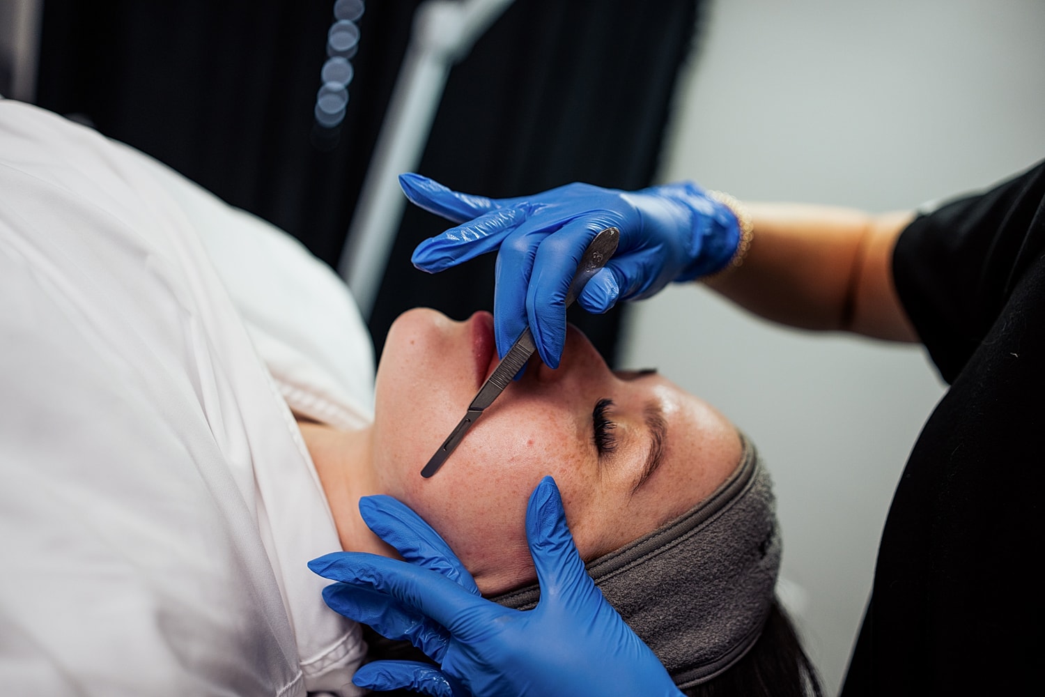 Skincare professional performing facial treatment on client.