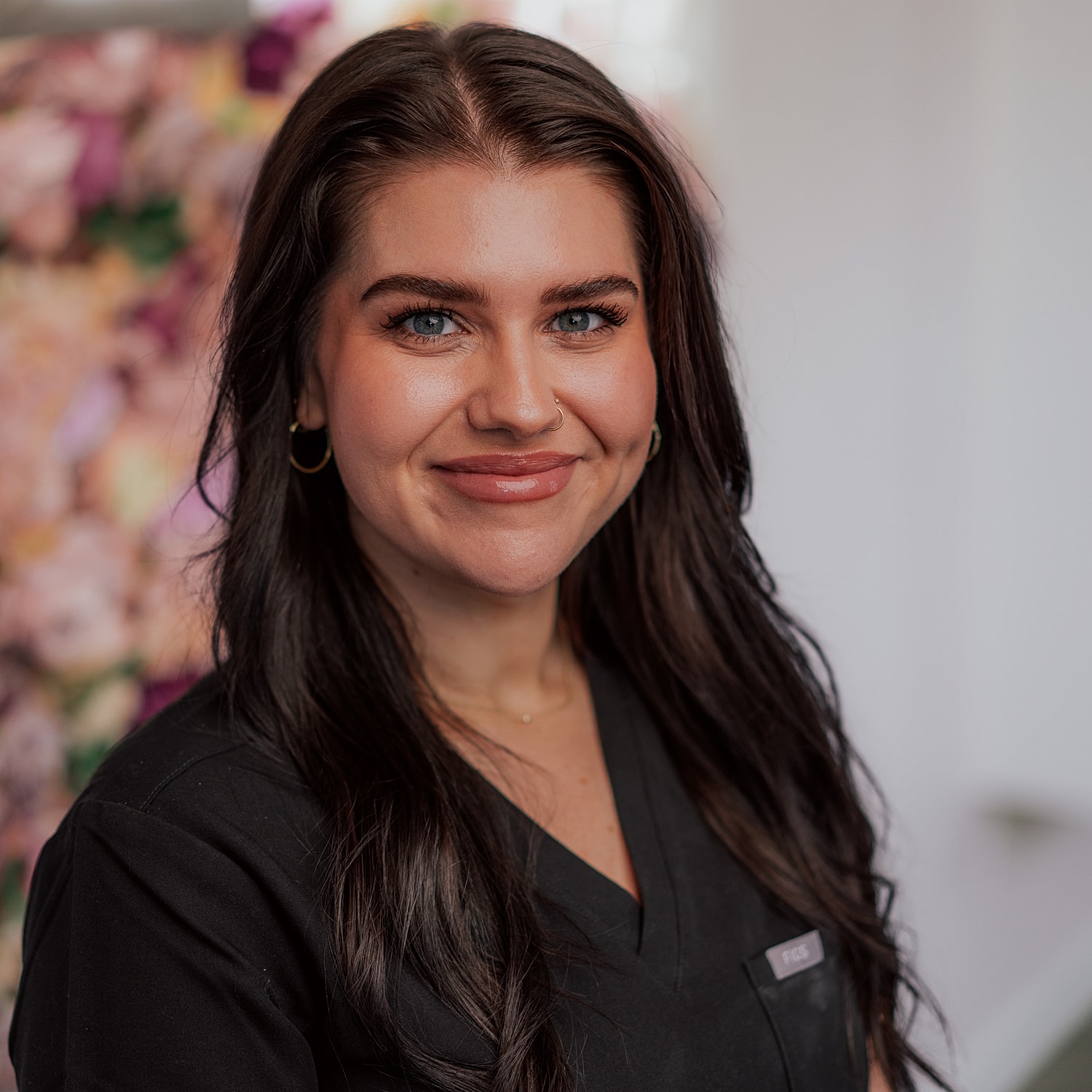 Smiling woman in professional attire against floral background.