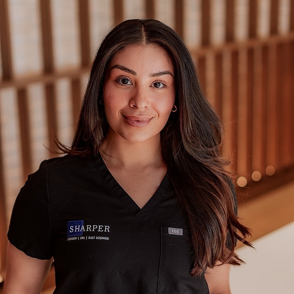 Woman in medical attire smiling confidently.