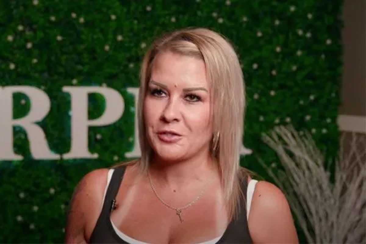 Woman speaking in front of green backdrop.