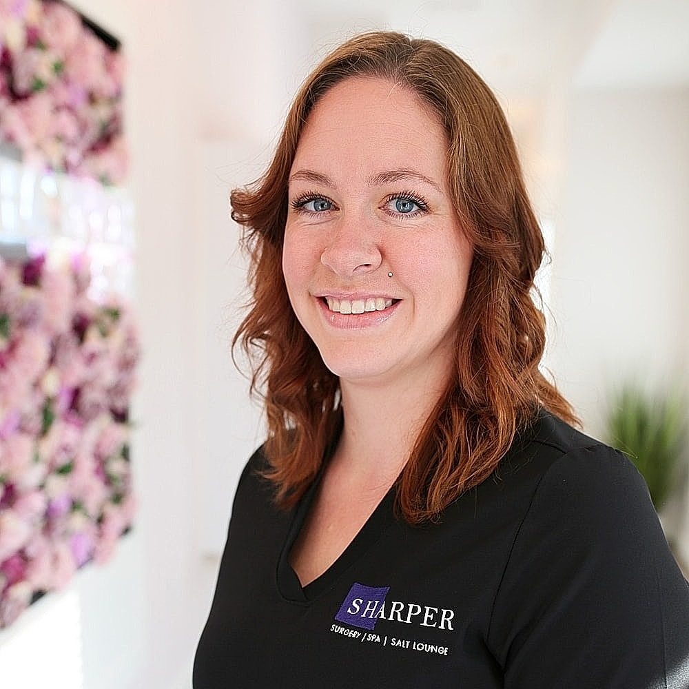 Smiling employee in professional spa uniform.