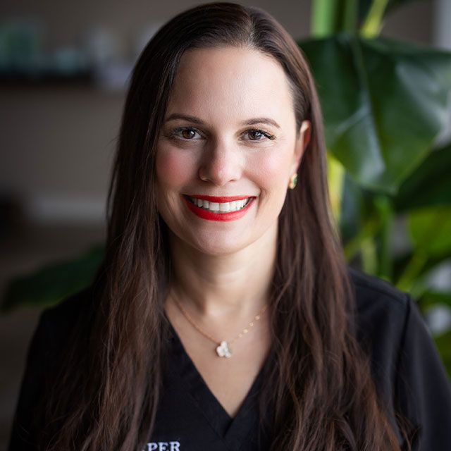 Smiling woman in professional attire, plant background.