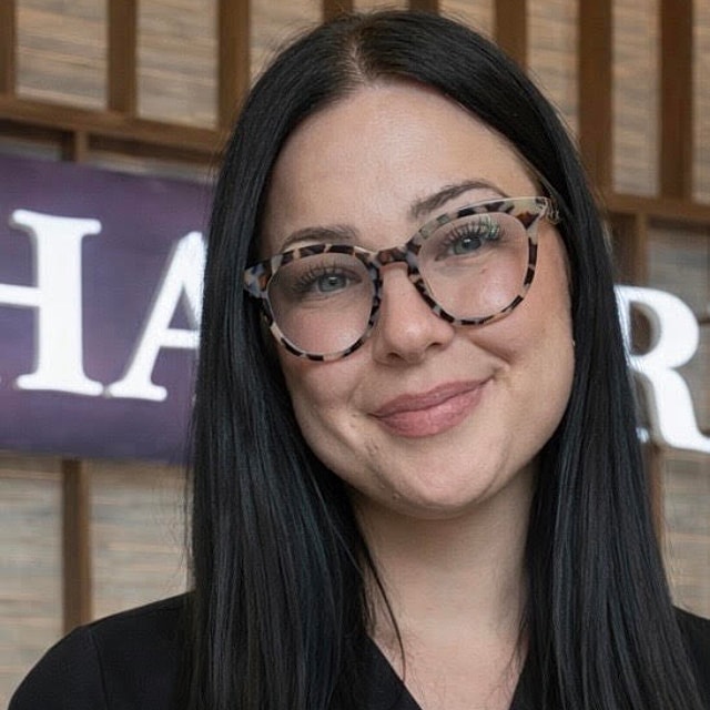 Woman with glasses smiling at the camera.