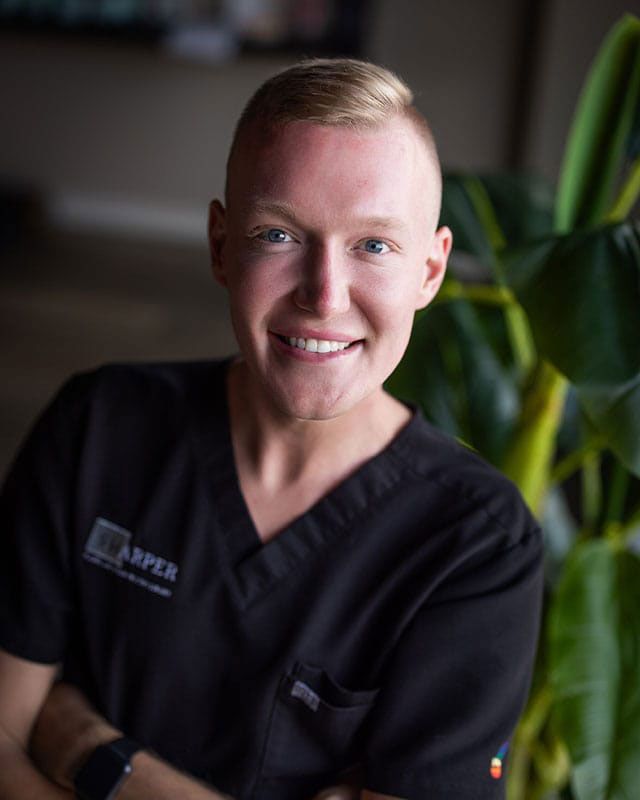Smiling individual wearing black medical scrubs.