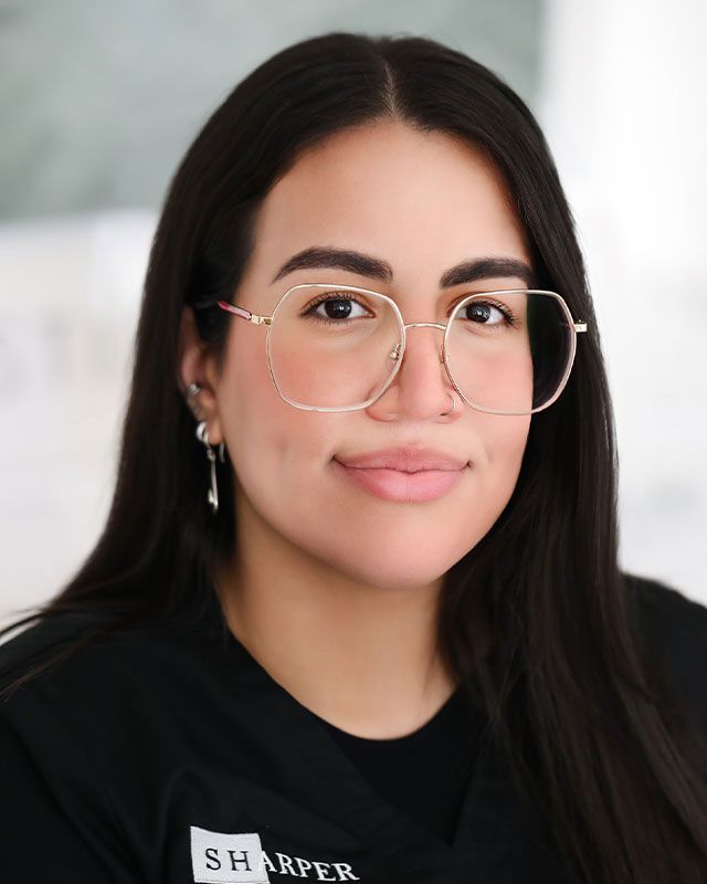 Woman with glasses smiling in professional attire.
