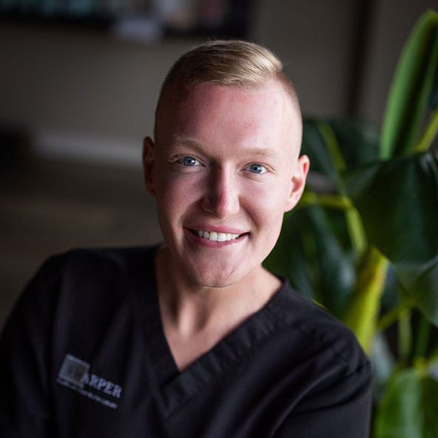 Smiling person in medical scrub attire indoors.