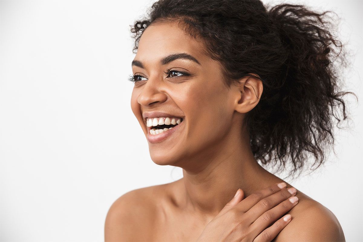 Smiling woman with curly hair against white background.