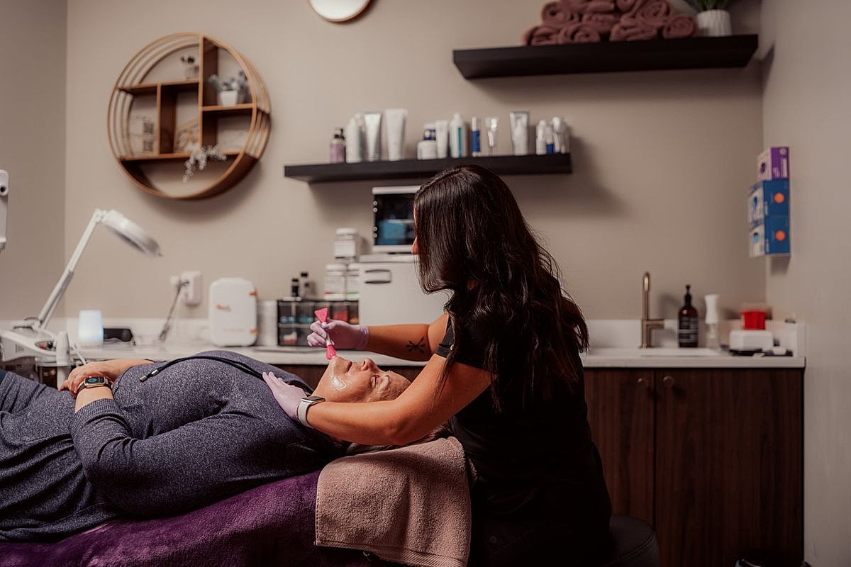 Esthetician performing facial treatment on a client.