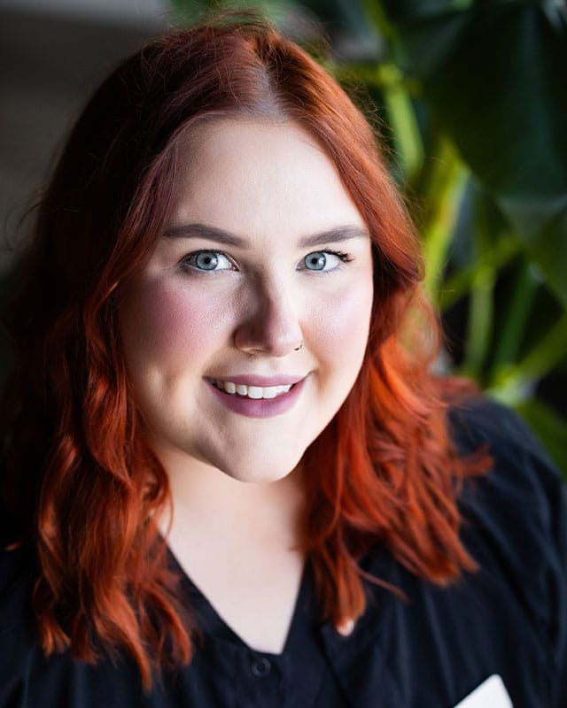 Smiling person with red hair and soft background.
