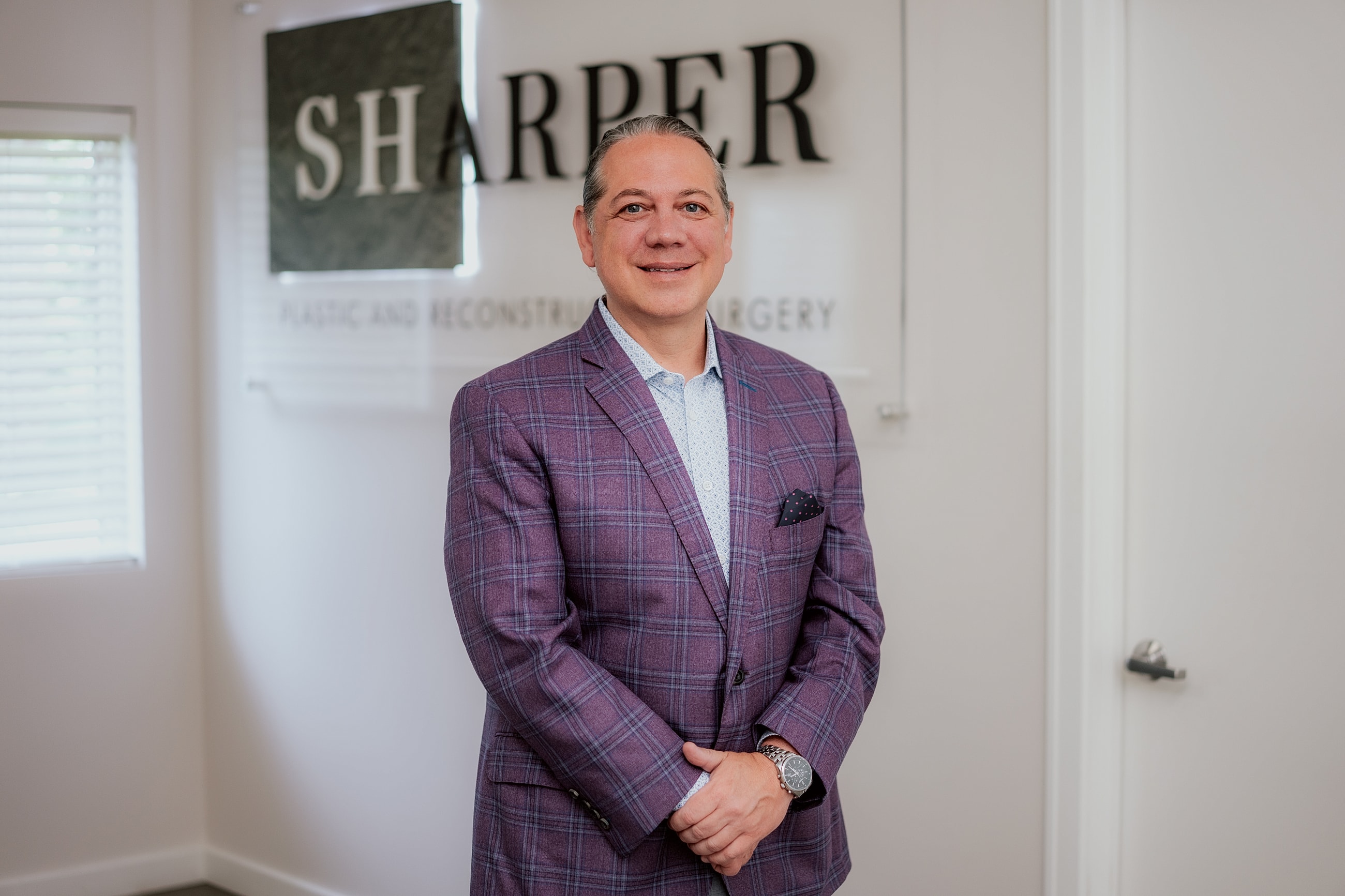 Male professional posed in plastic surgery office.