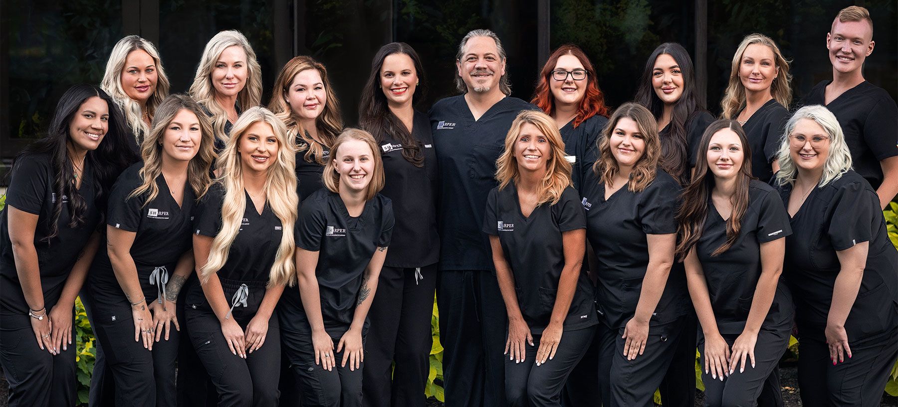 Healthcare team posing outdoors in black scrubs.