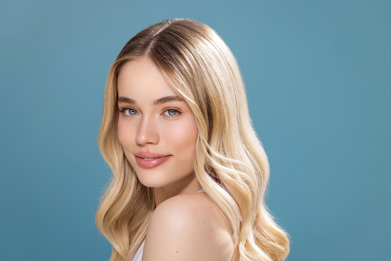 Young woman with wavy blonde hair and blue background.