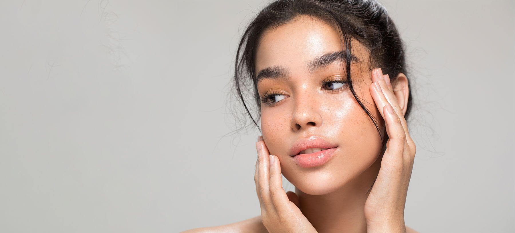 Woman with smooth skin, touching her face.